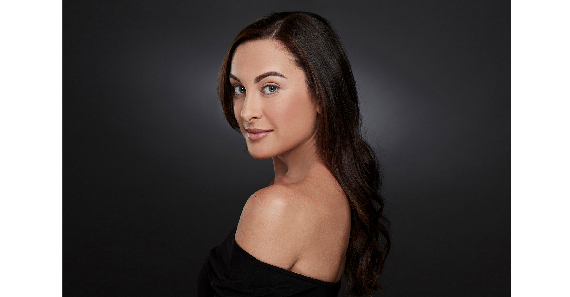 Female actress  headshot turning towards camera on dark grey backdrop